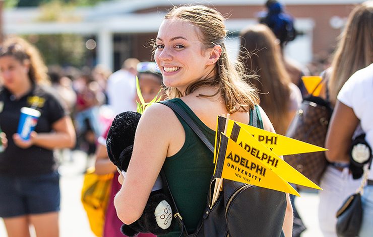 A student at a social event on campus with ӰƬ University flags in her backpack