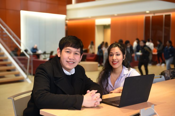 Male and female 成人影片 students together in the Nexus Building lobby on a laptop.