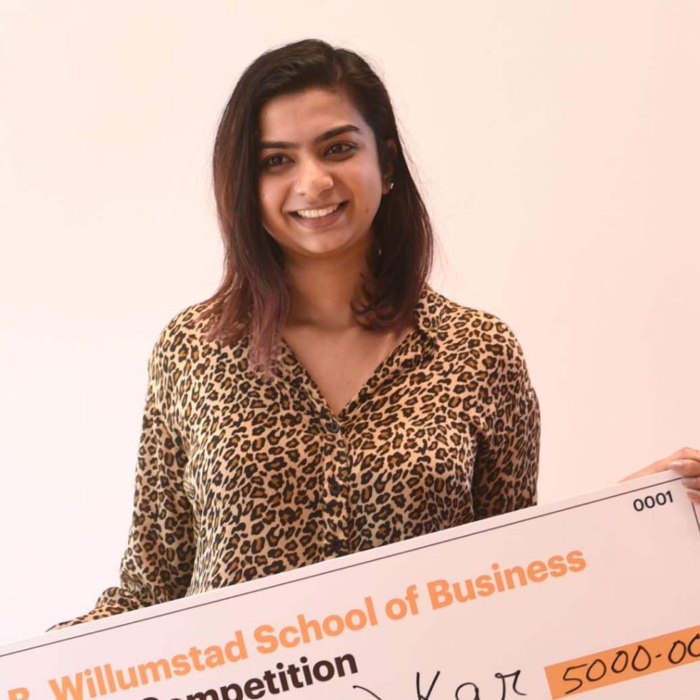 ӰƬ student Pooja Kar holding a check after winning the Business Plan Competition.
