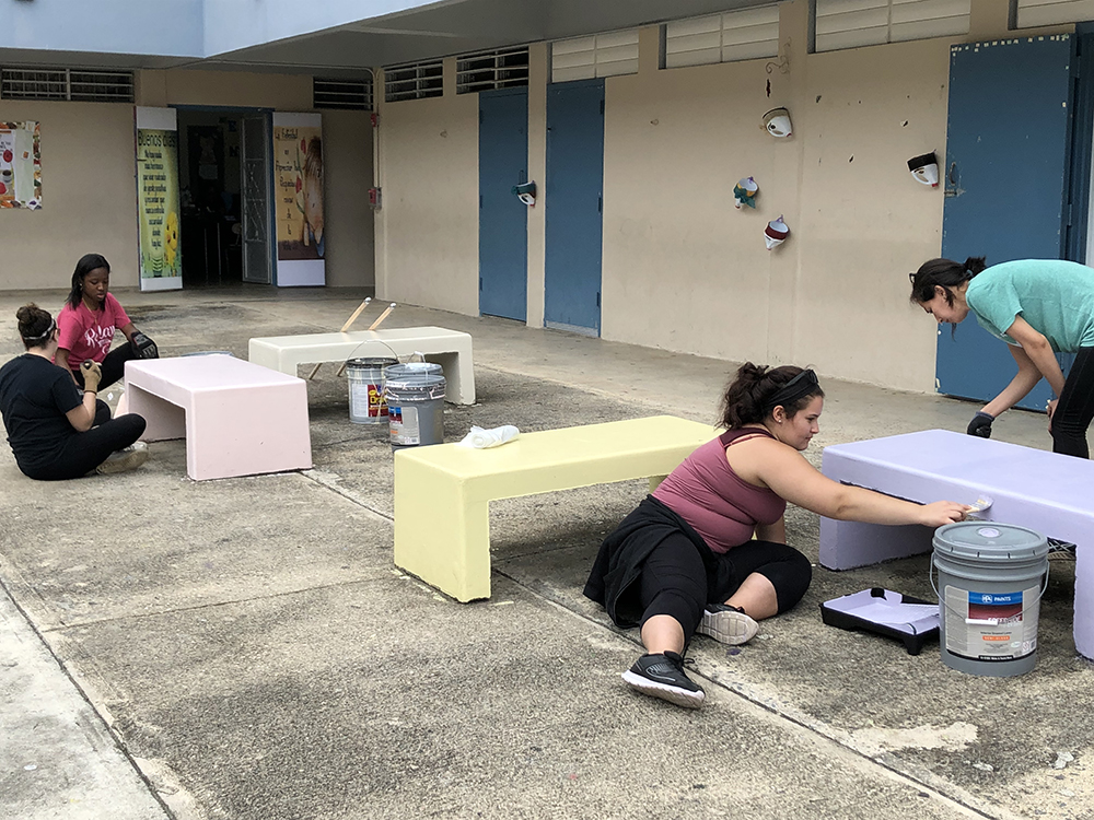 ӰƬ students painting outdoor space at a local school.