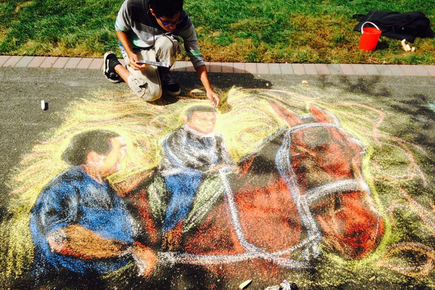 ӰƬ student drawing a horse and rider chalk design for the 2021 Fall Arts Festival.