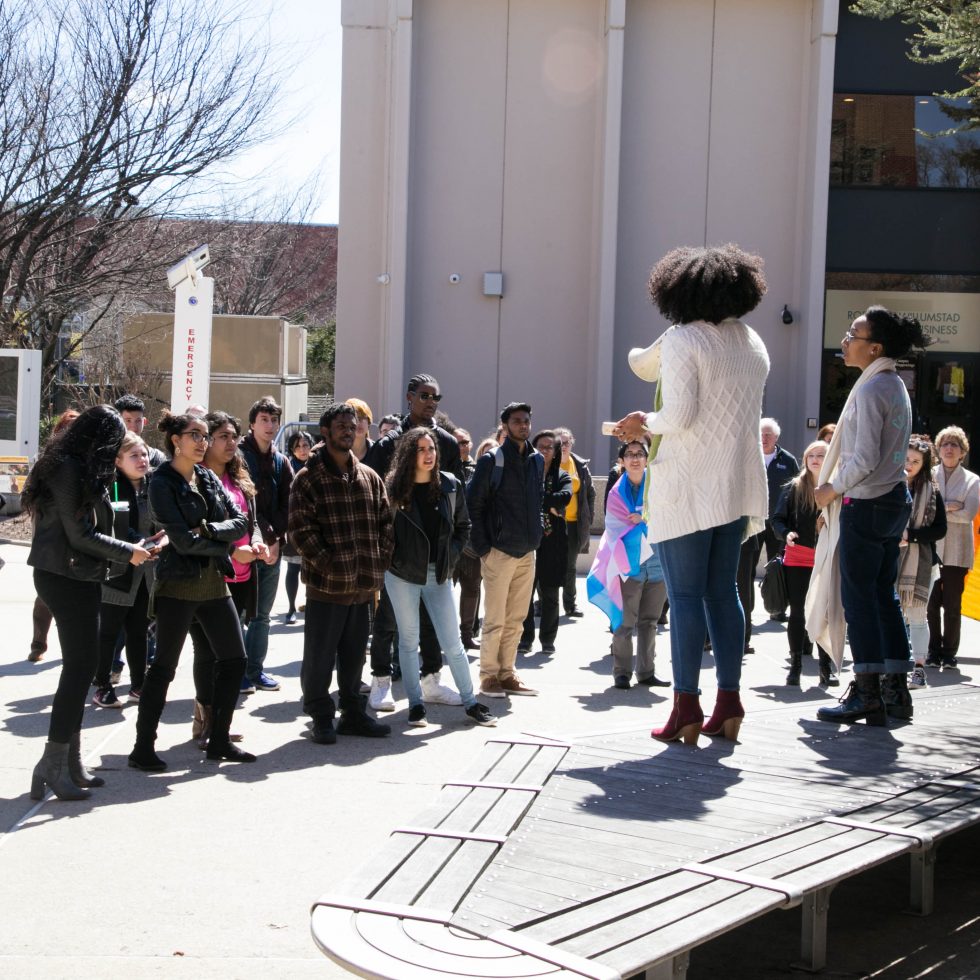 ӰƬ student holding a bullhorn stands in front of a crowd