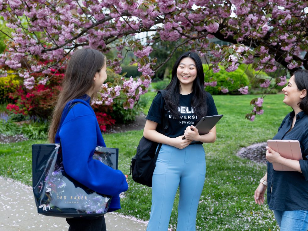 A group of ӰƬ students on campus with cherry blossoms in the background