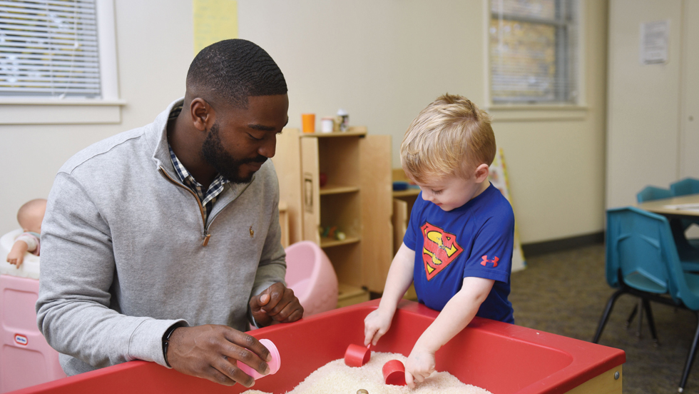 An ӰƬ student works closely with a young child in the Early Learning Center