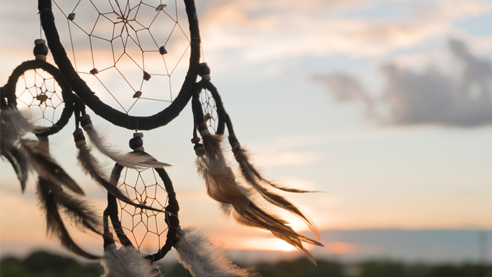 close-up of a dream catcher with sunset sky in background