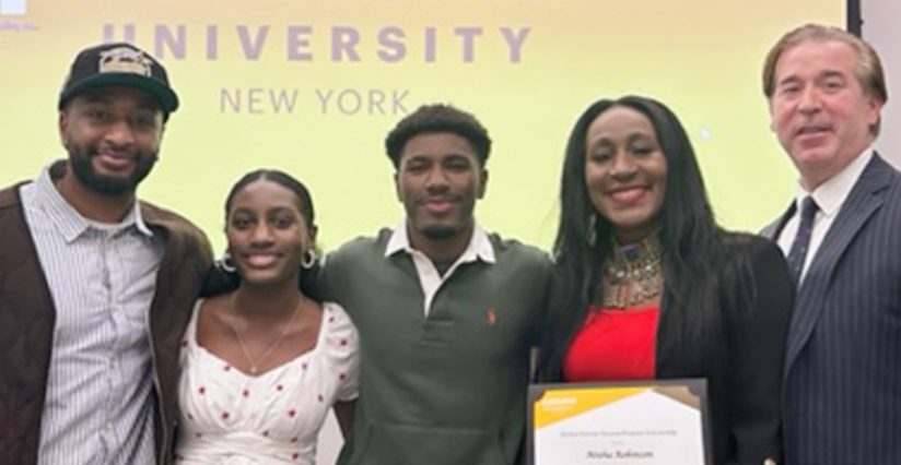 Atisha Robinson holds her award certificate. Her partner is on her left, while three of her children—a two young men and a young woman—are at her right. The ӰƬ logo is projected onto a screen that stands behind them.