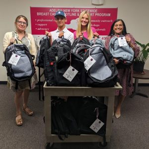 Three women and one man smiling and holding backpacks